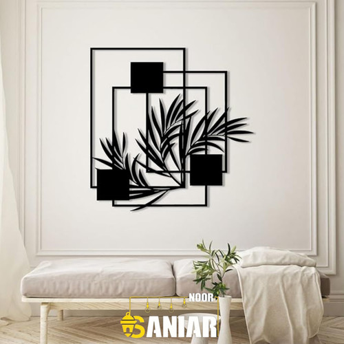 تابلو دکوراتیو مشکی مدرن با طرح برگهای گیاه و قابهای مستطیلی متداخل بر روی دیوار سفید بالای یک کاناپه کرم».