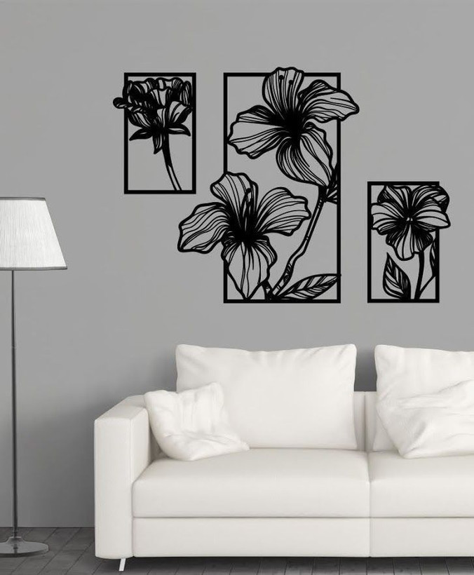 ست سه عددی تابلو دکوراتیو مشکی با طرح گلهای خطی انتزاعی که به صورت پلهای روی دیوار طوسی بالای کاناپه سفید نصب شدهاند».