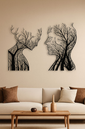 ست دو عددی دیوارکوب مشکی فلزی شامل نیمرخ زن و مرد که با طرح شاخههای درخت ترکیب شدهاند، نصب شده روی دیوار کرم بالای کاناپه سفید».