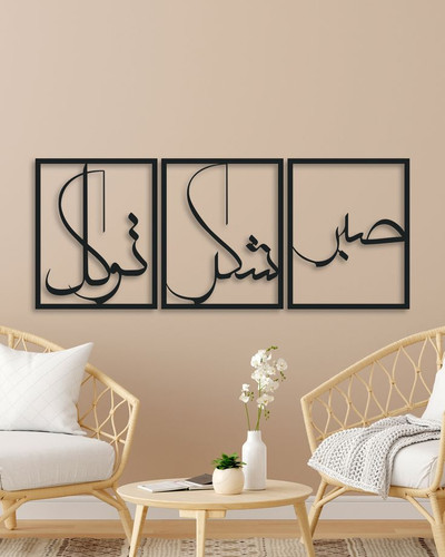 ست سه عددی قاب مستطیلی مشکی فلزی با کلمات خطاطی شده صبر، شکر و توکل نصب شده روی دیوار کرم بالای صندلیهای حصیری».