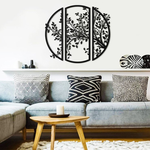 ست سه تایی دیوارکوب مشکی فلزی که در کنار هم طرح یک دایره بزرگ با شاخ و برگهای درخت را تشکیل میدهند، نصب شده روی دیوار سفید بالای کاناپه طوسی».