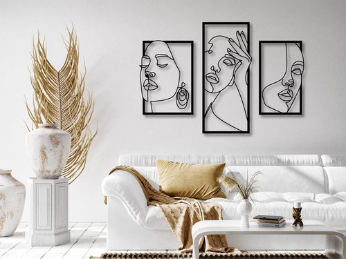 ست سه تایی قاب فلزی مشکی با طرحهای خطی از چهره زن که قاب میانی بلندتر از دو قاب کناری است، نصب شده روی دیوار سفید بالای کاناپه مدرن