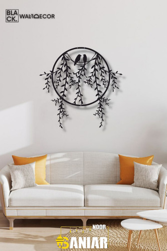 یک تابلو فلزی دایرهای مشکی با طرح دو پرنده روی شاخههای بید که برگهای آن از کادر دایره بیرون زده و روی دیوار سفید بالای مبل کرم نصب شده است».