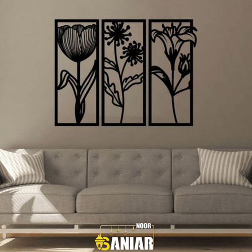 ست سه تایی قاب فلزی مشکی عمودی با طرحهای مختلف گلهای بهاری، نصب شده به صورت متقارن روی دیوار طوسی تیره بالای یک کاناپه راحتی طوسی روشن».