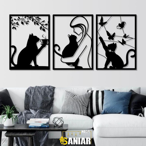 «ست سه تایی قاب فلزی مشکی با طرحهای گربه در حال نوشیدن قهوه، گربه در آغوش دختر و گربه در حال بازی با پروانهها، نصب شده روی دیوار سفید بالای کاناپه مدرن».