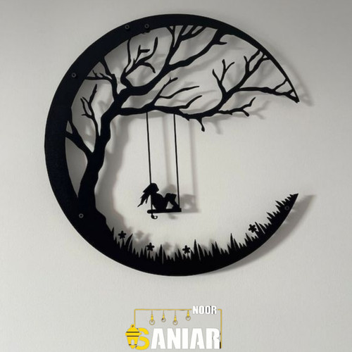یک دیوارکوب فلزی گرد مشکی با طرح دختری که روی یک تاب آویزان از شاخه درخت در میان هلال ماه نشسته است، نصب شده روی دیوار سفید اتاق خواب».