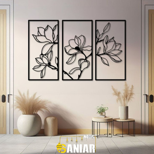 ست سه تایی قاب فلزی مشکی با طرحهای به هم پیوسته گل ماگنولیا، نصب شده روی دیوار کرم روشن در یک فضای ورودی مدرن با گلدانهای تزیینی».