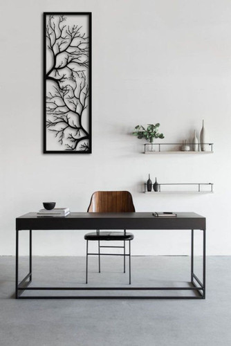 «یک تابلو فلزی مشکی کشیده با طرح شاخههای درخت که روی دیوار سفید بالای یک میز کار مدرن نصب شده است.»