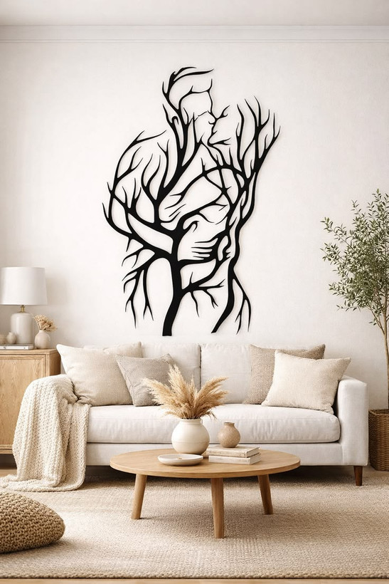 یک تابلو فلزی مشکی طرح لاینآرت که در هم تنیده شدن بدن انسان و شاخههای درخت را نشان میدهد و روی دیوار سفید یک نشیمن مدرن نصب شده است.»